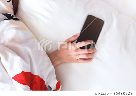 Hand sleeping and holding a mobile phone on bed. 35430228