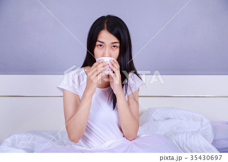 woman drinking acup of coffee on bed in bedroom 35430697
