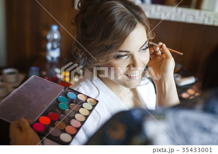 makeup artist preparing bride before the wedding 35433001