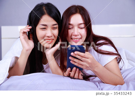 two woman using a phone in her hand on bed in bedroom 35433243