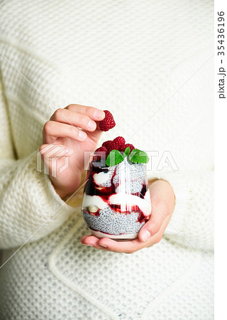 Girl in white sweater holds glass with chia milk Girl in white sweater holds glass with chia milk 35436196
