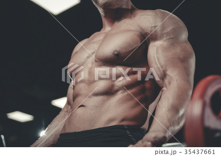 Handsome model young man training arms in gym Handsome model young man training arms in gym 35437661