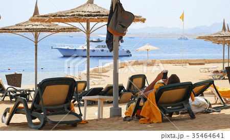 Man is lying on the beach couch under the umbrella Man is lying on the beach couch under the umbrella 35464641