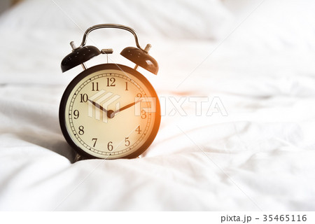 Alarm clock on the white bed. Holiday and reminder 35465116