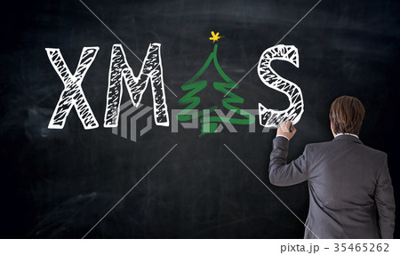 Businessman writes XMAS on blackboard concept 35465262