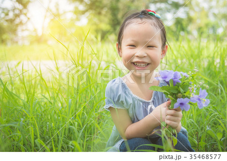 Little girl smiling while holding flower in graden 35468577