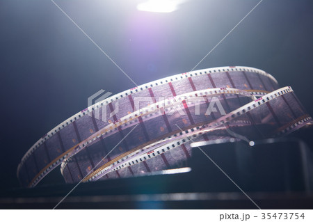 Old film with a movie on a dark background Old film with a movie on a dark background 35473754