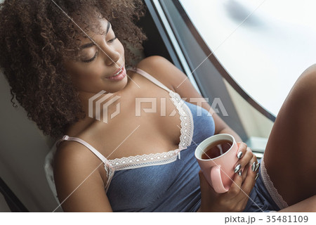 Cheerful girl tasting mug of tea Cheerful girl tasting mug of tea 35481109