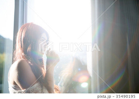 Long-haired pensive girl with cup of tea by window 35490195