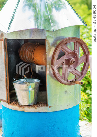 a well with water and a metal bucket near him a well with water and a metal bucket near him 35499004
