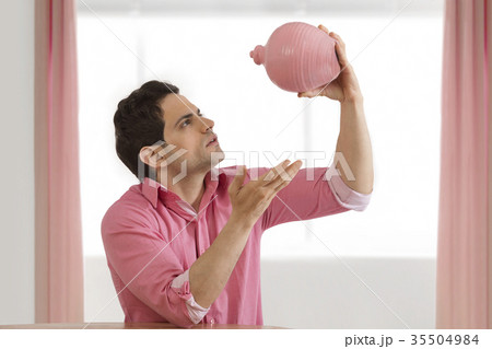 Man shaking piggy bank 35504984