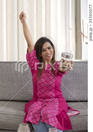 Woman cheering with jar of change Woman cheering with jar of change 35505077