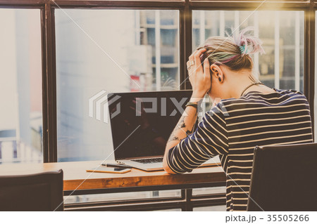 Back side of Depressed Hipster young Woman freelancer thinking about her job in serious action which have technology Laptop in the Loft cafe workplace. Creative Startup and entrepreneur business concept 35505266