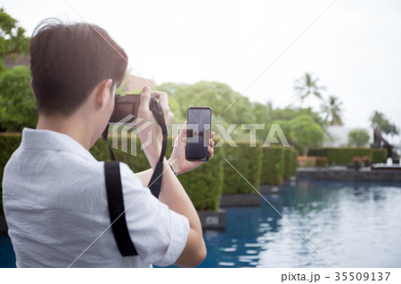 Man tourist with compact camera and cell phone  35509137