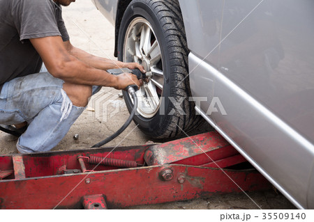 Mechanic changing car wheel with ipneumatic wrench 35509140