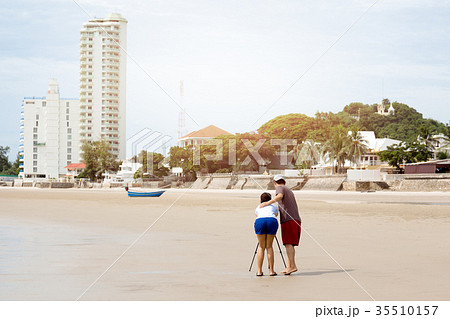 Couple taking picture using tripod on the beach 35510157