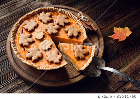 Homemade pumpkin pie with slice cut out on wooden 35511760