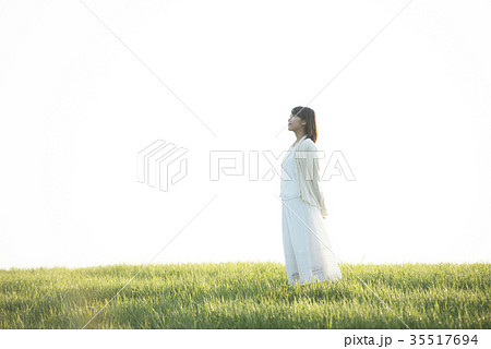 草原で空を見上げる女性の写真素材