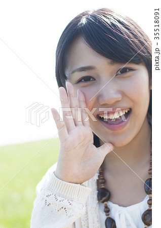 口元に手をあて微笑む女性の写真素材