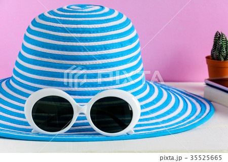 Blue hat and white sunglasses pink wall background Blue hat and white sunglasses pink wall background 35525665