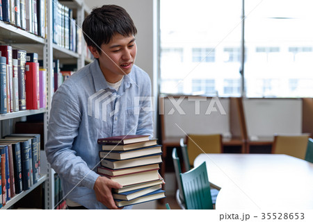 図書館で山積みの本をもつ学生 図書館で山積みの本をもつ学生 35528653