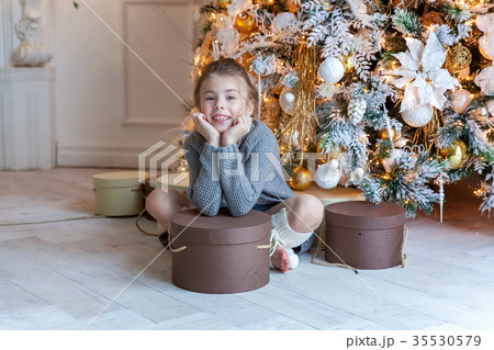 Young girl opens a gift under a Christmas tree 35530579