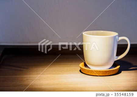 A cup of coffee is placed on a wooden floor. A cup of coffee is placed on a wooden floor. 35548159