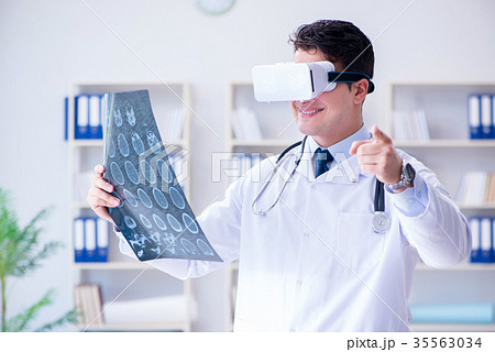 Young doctor looking at MRI scan through VR Young doctor looking at MRI scan through VR 35563034
