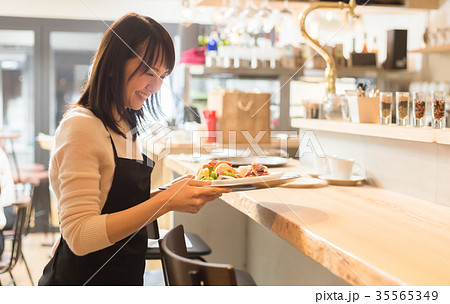 料理を運ぶカフェ店員の写真素材