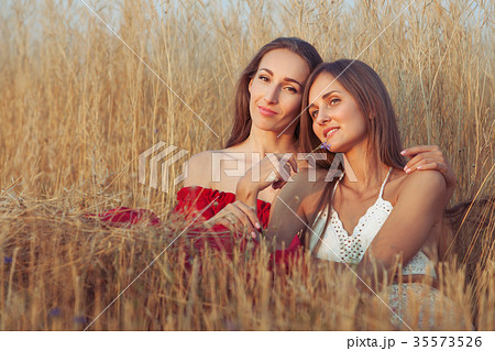 Young women are sitting in tall grass. Young women are sitting in tall grass. 35573526