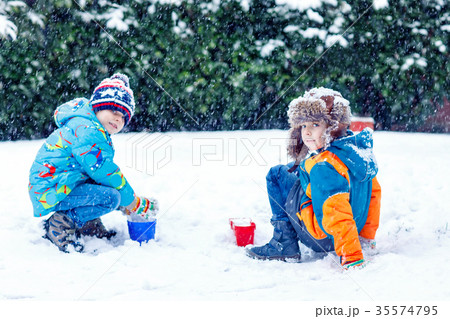 Two little kid boys playing with snow outdoors Two little kid boys playing with snow outdoors 35574795