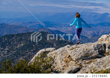 Young woman walking on rocky top of the mountain 35578880