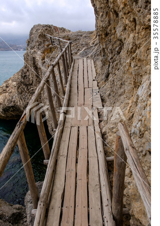 Flimsy old bridge across the rocks on sea coast 35578885