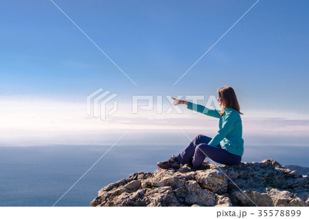 Woman sitting in a rocky top of the mountain Woman sitting in a rocky top of the mountain 35578899