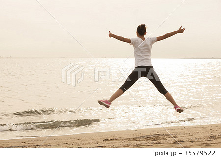 海でジャンプする女性の写真素材