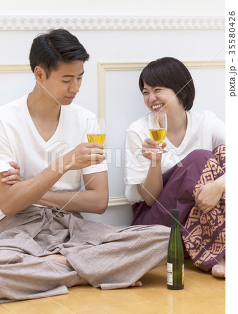床に座ってグラスを傾けるカップル 35580426