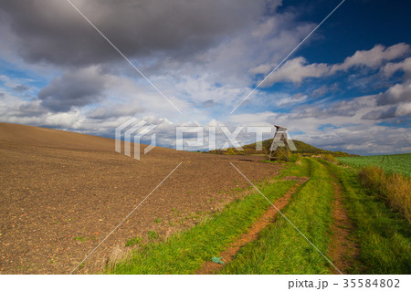 Huntig tower on the empty road between fields 35584802