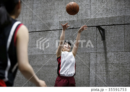 バスケをする女性 シュートの写真素材