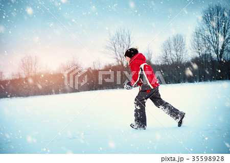Child in winter clothes playing with snowballs 35598928