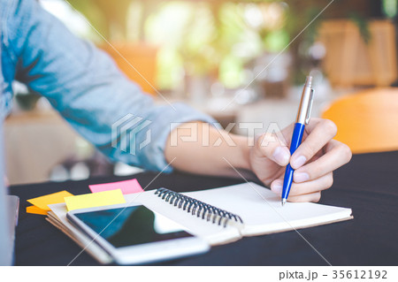 Woman hand is writing on notepad with a pen Woman hand is writing on notepad with a pen 35612192