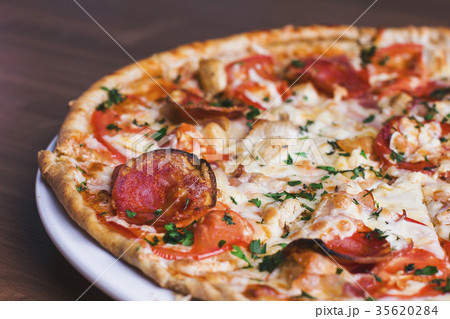 fresh baked pizza with salami on wooden background 35620284