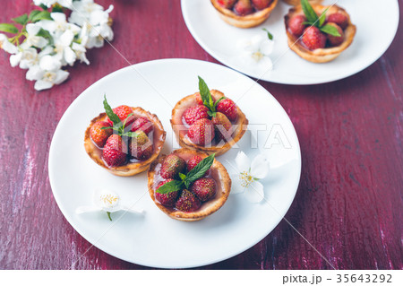 Strawberry tartlet on white plates on red Strawberry tartlet on white plates on red 35643292