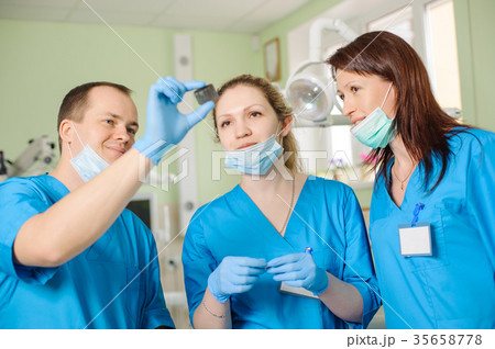 Male dentist showing x-ray to female assistant at dental clinic Male dentist showing x-ray to female assistant at dental clinic 35658778