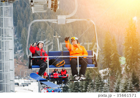 Skier and snowboarder riding up on ski lift Skier and snowboarder riding up on ski lift 35661571