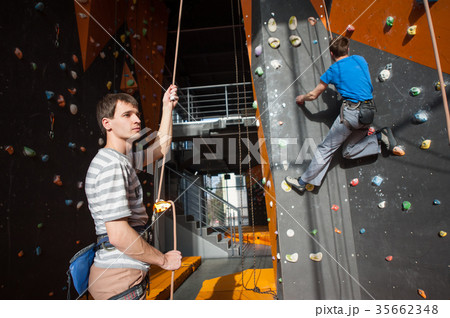 Belayer insuring the climber on rock wall indoors 35662348