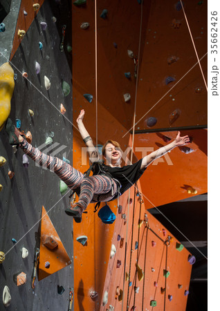 Female climber is climbing up on indoor rock-climbing wall Female climber is climbing up on indoor rock-climbing wall 35662426
