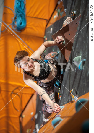 Female climber is climbing up on indoor rock-climbing wall 35662428