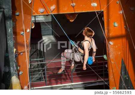 Female climber is climbing up on indoor rock-climbing wall Female climber is climbing up on indoor rock-climbing wall 35662593
