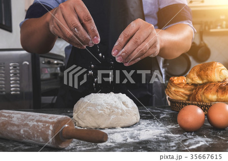 Close up of Man hands sprinkling flour over fresh dough with ing Close up of Man hands sprinkling flour over fresh dough with ing 35667615
