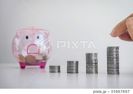 Businessman putting coins increase growth at a desk and a piggy Businessman putting coins increase growth at a desk and a piggy 35667697